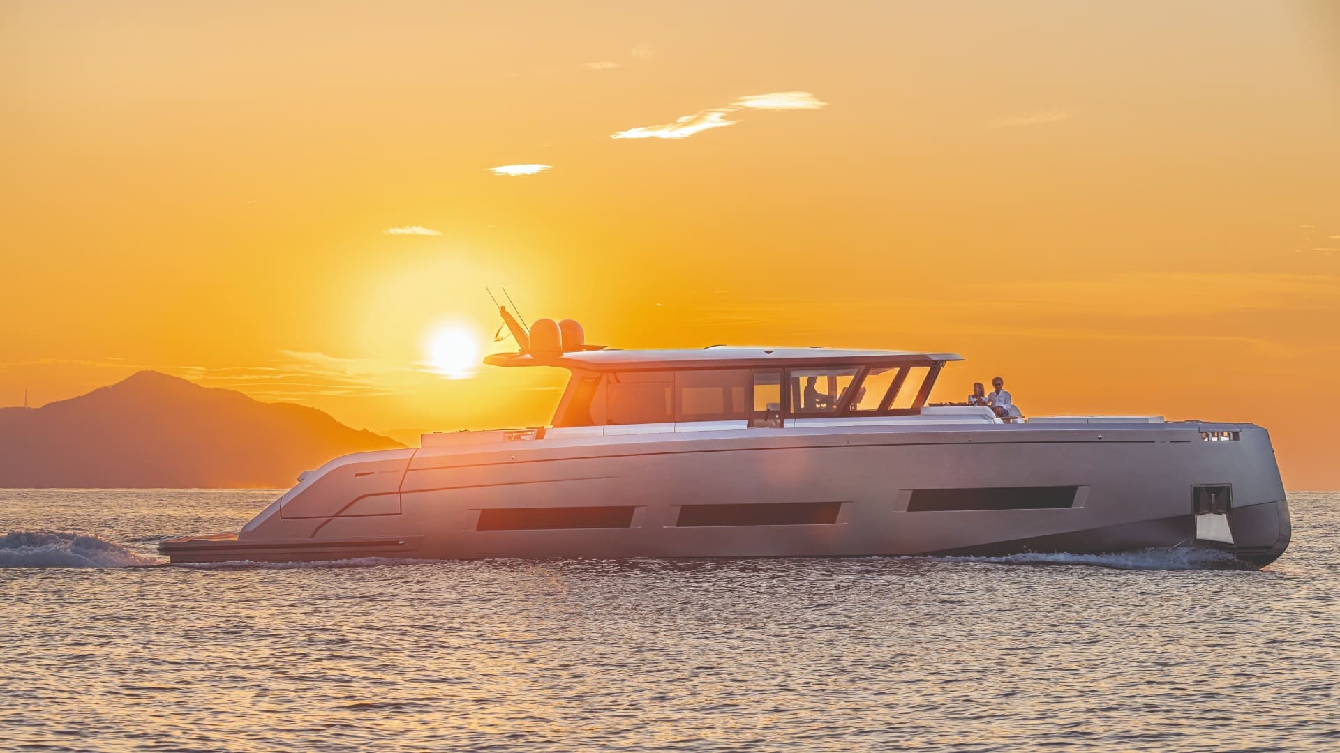 Bateau naviguant au coucher du soleil près des côtes corses de Porto Vecchio avec montagnes